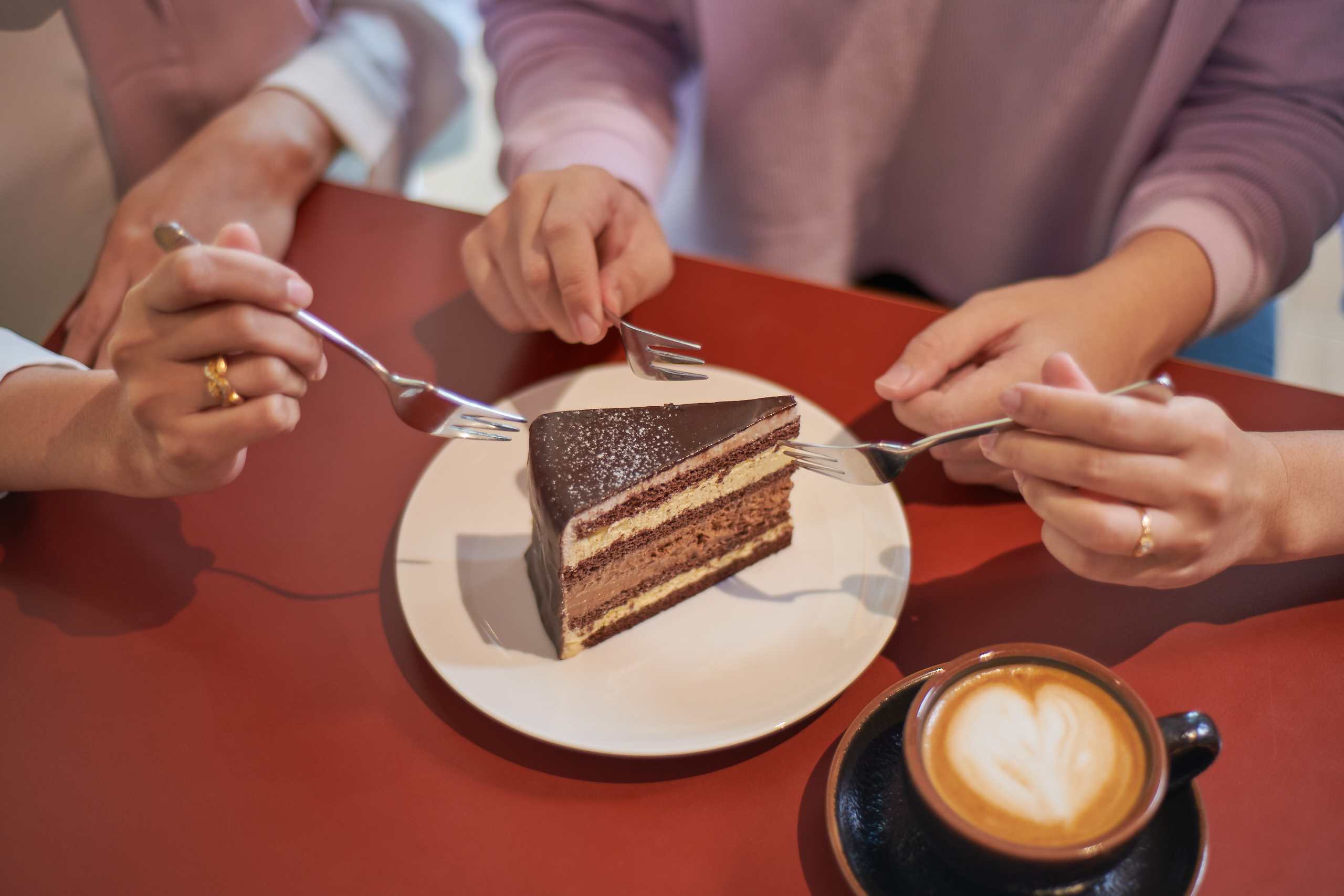 Friends sharing a slice of delivered birthday cake with coffee